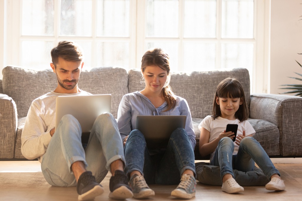 family-with-kid-sitting-on-floor-at-home-using-devices-picture-id1130696772